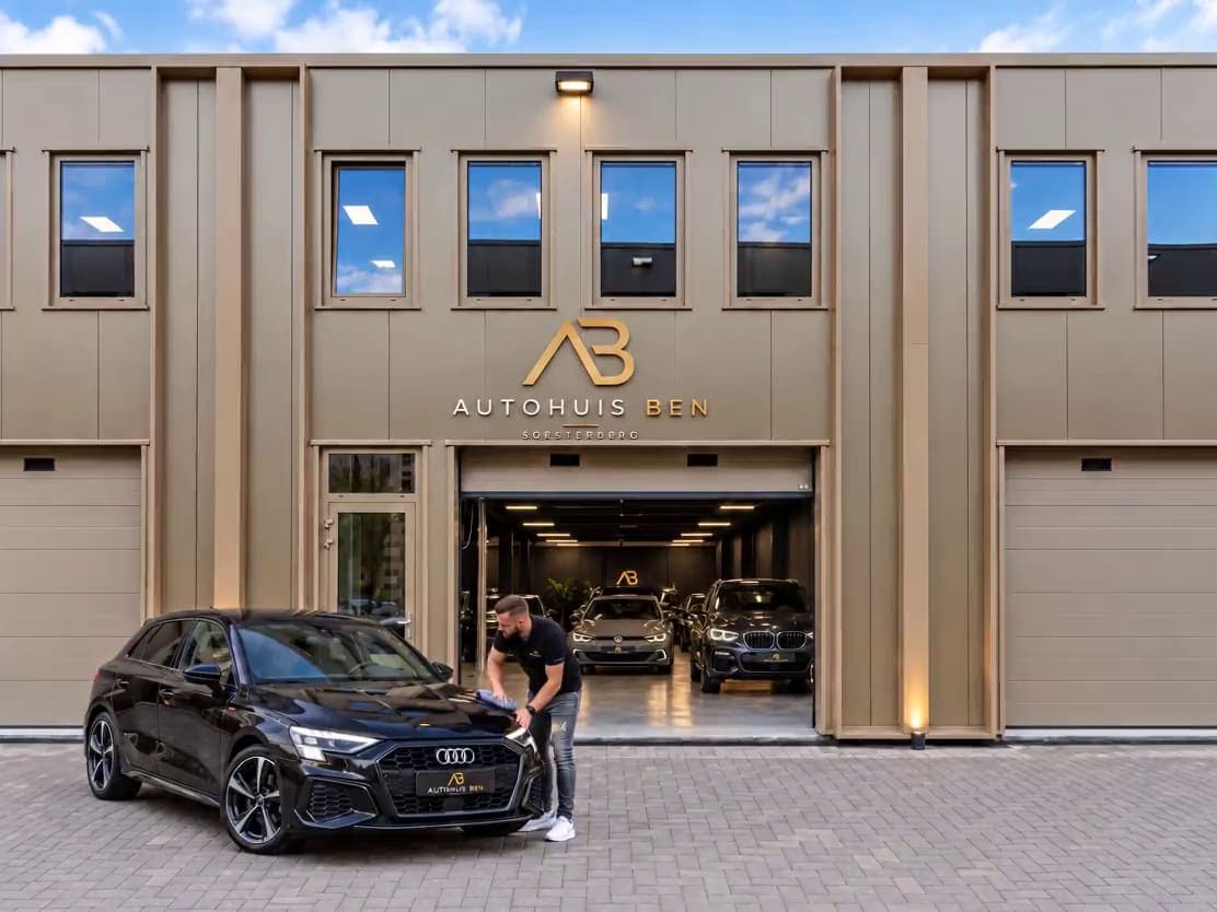 De gevel van Autohuis Ben aan de Amersfoortsestraat in Soesterberg, met een zwarte Audi voor de open showroom