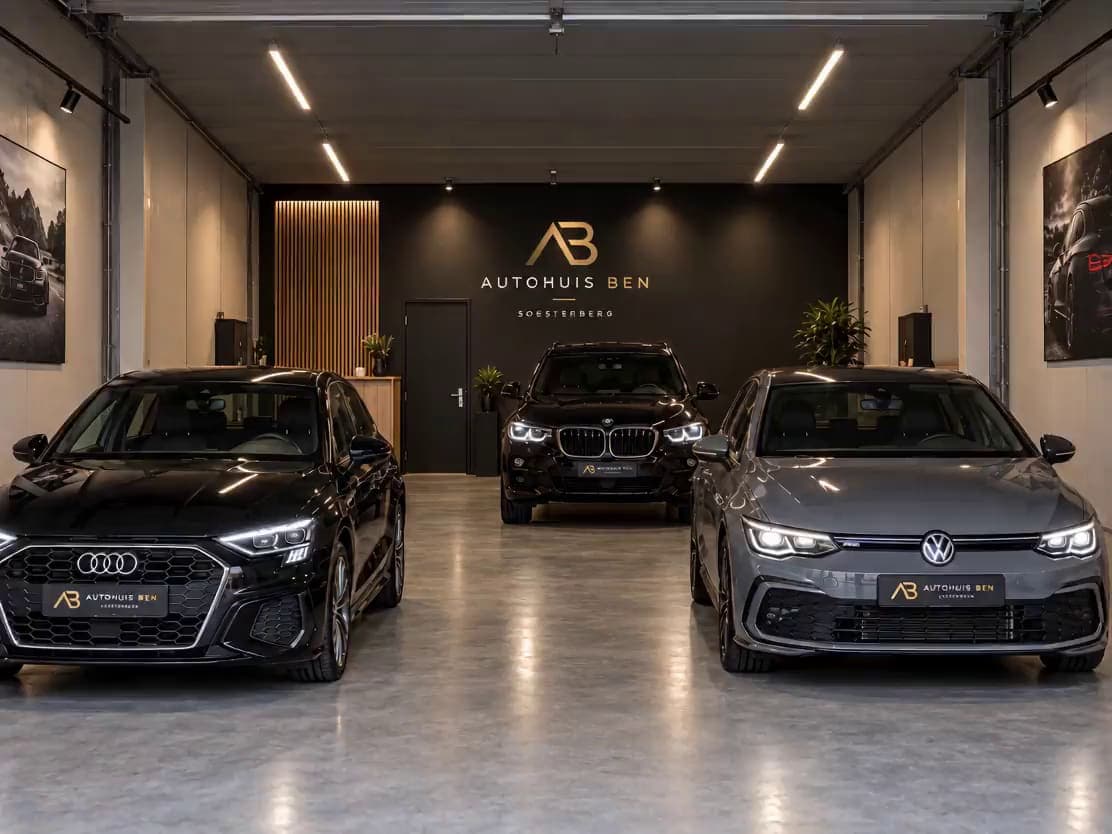 De showroom van Autohuis Ben: drie auto's onder de lichtlijnen, met het logo op de achterwand
